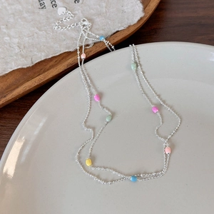 Dettaglio della catena d'argento a due strati con perline colorate e ciondolo a cuore