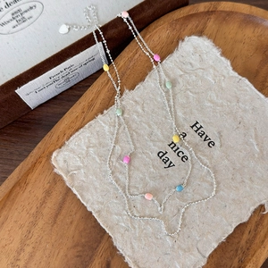 Dettaglio di collana a catena d'argento con perline colorate su vassoio rustico
