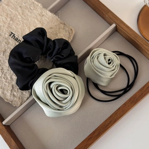 Close-up of mint green silk rose flower scrunchie and hair tie in a wooden tray