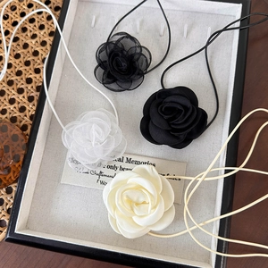 Colliers choker élégants avec roses en organza et satin en noir et blanc sur un plateau