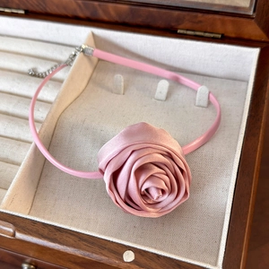 Close-up of pink satin rose choker necklace with adjustable chain in a wooden jewelry box