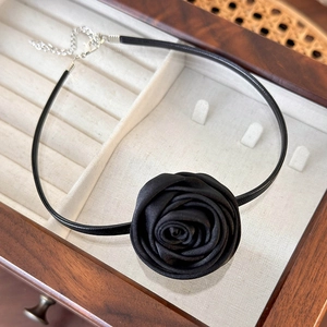 Detail of a vintage black satin rose choker featuring a soft leather cord and silver clasp