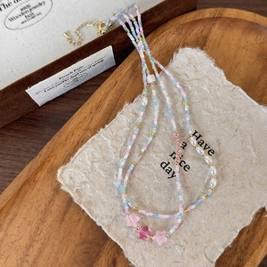 Dettaglio della collana di perle colorate con stelle rosa e perle bianche su un vassoio