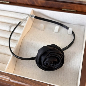 Detail of a black fabric rose choker with an adjustable silver chain in a wooden box
