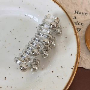 Close-up of pearl telephone wire hair ring with silver beads on a white ceramic plate
