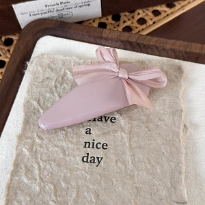 Détail d'une pince à cheveux goutte en cuir rose avec nœud sur papier texturé élégant