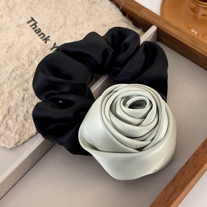 Detailed close-up of the mint green satin rose flower hair tie on an elegant display tray