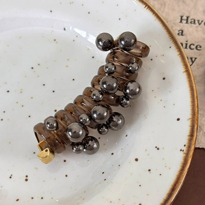 Macro shot of amber spiral banana hair clip with metallic beads and gold buckle
