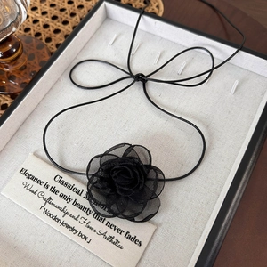 Détail macro du choker rose en maille noire avec pétales superposés et liens fins