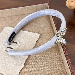 Detailed view of handmade light blue headband with rhinestone butterfly and satin fabric