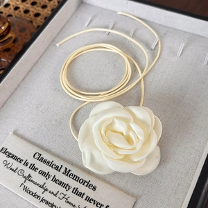 Détail de tour de cou rose en satin crème avec pétales superposés et cordon fin