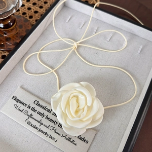 Gros plan d'un collier choker fleur de soie beige dans un coffret à bijoux chic