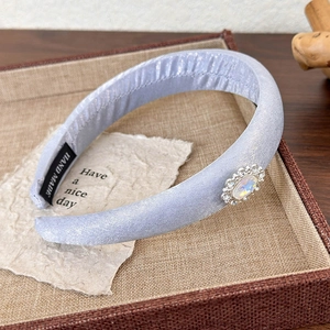 Close-up of padded lilac satin headband with rhinestone jewel and Hand Made label