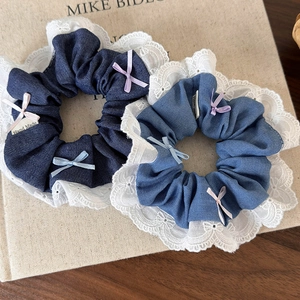 Detail of denim hair scrunchies with white lace edges and colorful ribbon bows