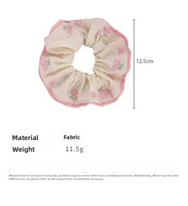 Detailed size view of the cream fabric scrunchie with pink embroidered cherry patterns
