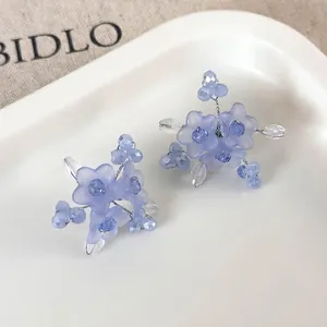 Blue floral bead earrings with matte petals and crystal accents on a ceramic tray
