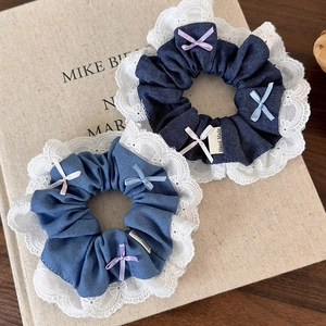 Close-up of denim scrunchies with white lace edges and colorful ribbon bows