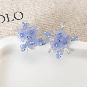 Detail of handmade light purple resin flower earrings with faceted beads on ceramic plate