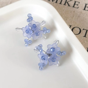 Handmade light blue flower stud earrings with beads and crystals on white tray