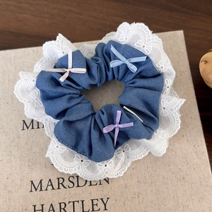 Detail of blue denim scrunchie featuring white lace trim and colorful mini silk bows