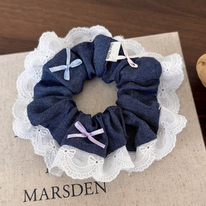 Detail of denim scrunchie with white lace edges and colorful ribbons for hair