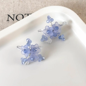 Macro view of blue floral beaded studs with translucent petals and handcrafted details