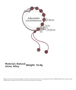 Détail du bracelet en perles de pierre avec breloques fleurs et cordon rouge