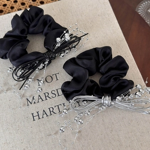 Detail of black satin hair scrunchies with silver bead bow and woven metallic cord