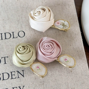 Three-piece set of satin 3D rose hair clips in cream, pink and green with gold accents