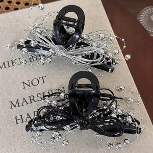 Detail of black hair claws featuring silver bead-embellished bows on textured books