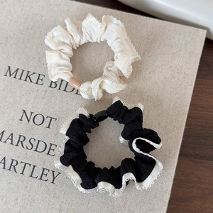 Close-up of white textured scrunchie and black hair tie with white lace edges
