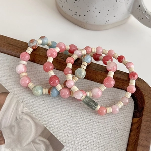 Detailed view of three-piece pink and green stone beaded bracelets on wood frame