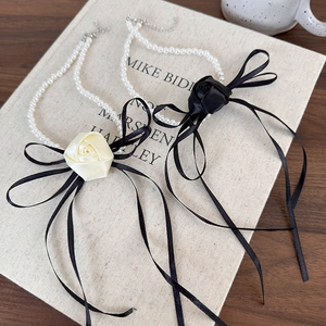 Detail view of French vintage pearl necklaces with satin rose and black ribbon bow