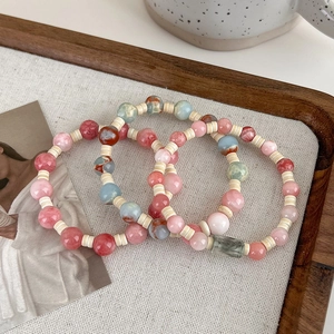 Close-up of pink and blue beaded bracelets in a wooden tray with a bohemian style design
