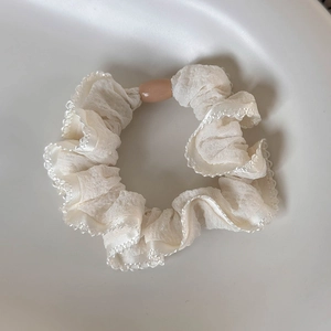 Detailed macro view of cream white polka dot scrunchie with lace edge and pink oval bead