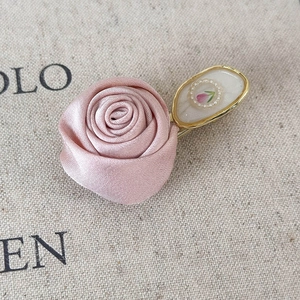 Detail of pink satin rose hair clip with an elegant golden framed tulip decorative piece