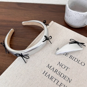 Detail of silver metallic headband and hair clip set with delicate black ribbon bows