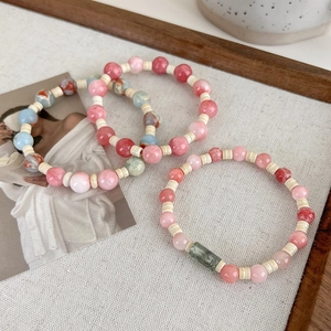 Close-up of pink and blue beaded bracelets set on white textured background