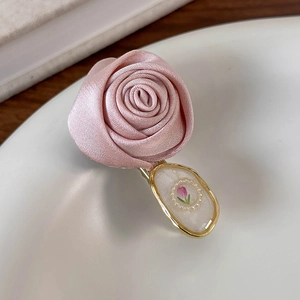 Close-up of a pink satin rose hair clip with a vintage floral beaded oval charm