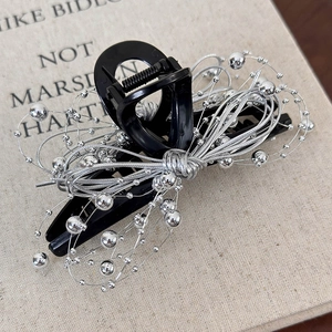 Close-up of silver beaded wire bow on large black hair claw clip with metallic finish
