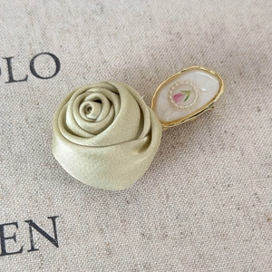 Detailed close-up of a satin gold 3D rose hair clip with an elegant oval floral centerpiece