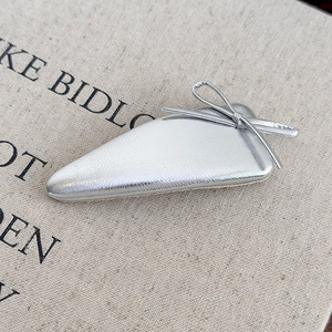 Detailed close-up of a silver bow hair clip featuring a cracked leather texture finish