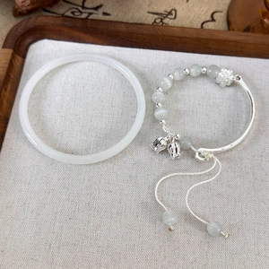 Vue macro détaillée du bracelet en perles d'opale avec breloque muguet sur plateau en lin