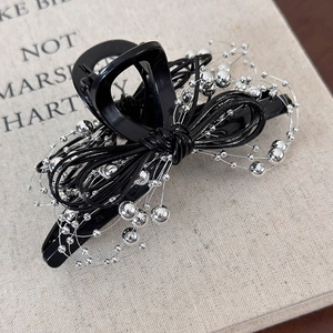 Detailed close-up of a black bow hair clip with silver metallic bead embellishments