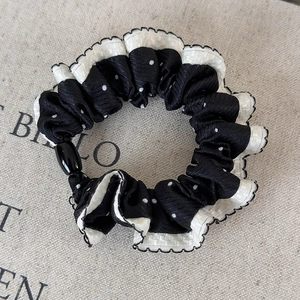Detail of polka dot scrunchie with white ruffle trim and a black bead embellishment