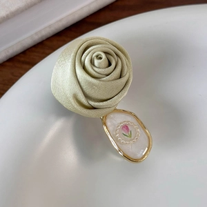 Macro detail of a 3D satin rose hair clip with an oval pendant and pearl tulip inlay