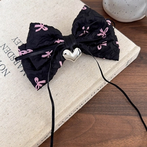 Vue détaillée d'une pince à cheveux Y2K noire avec nœuds roses et pendentif cœur en métal