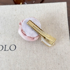 Detail view of the golden metal duckbill clip back with a pink satin flower and oval component