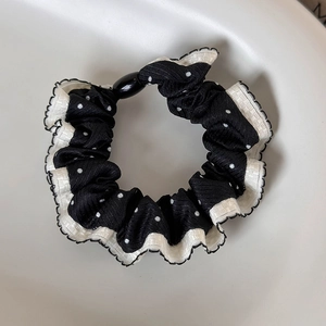 Detail of black polka dot hair scrunchie with white lace trim and decorative black bead