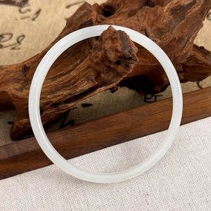 Vue détaillée d'un bracelet rond en jade blanc crème sur un support en bois Zen